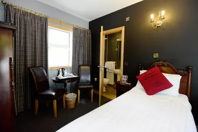 a bedroom with a bed with a red pillow on it at Rivendell in Dumfries