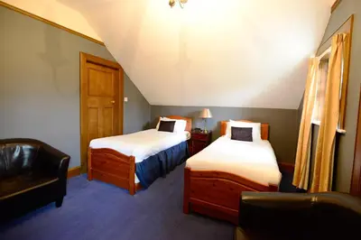 a small room with two beds and a chair at Rivendell in Dumfries
