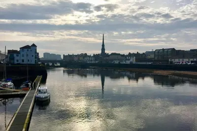 a boat is docked in a river in a city at The Mariners in Ayr