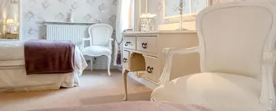 a white bedroom with a bed and a chair at Bessiestown Country Guesthouse in Carlisle