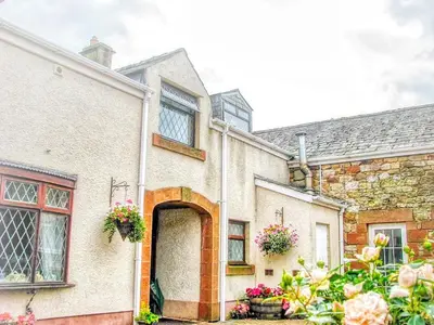 a brick house with a door and flowers in front at Bessiestown Country Guesthouse in Carlisle