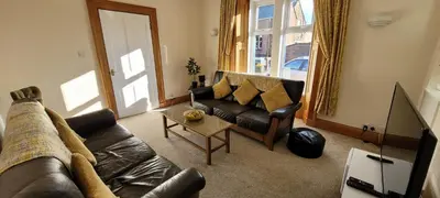 a living room with a leather couch and a table at Criffel Cottage in Dumfries