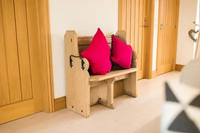 a wooden bench with two pink pillows on it at Galloway View in Castle Douglas