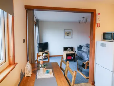 a kitchen and living room with a table and a refrigerator at Kestrel Lodge in Beeswing
