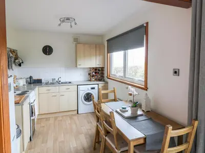a kitchen with a table and a table and chairs at Kestrel Lodge in Beeswing