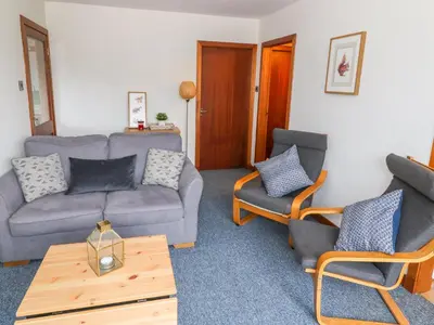 a living room with a couch and two chairs at Kestrel Lodge in Beeswing