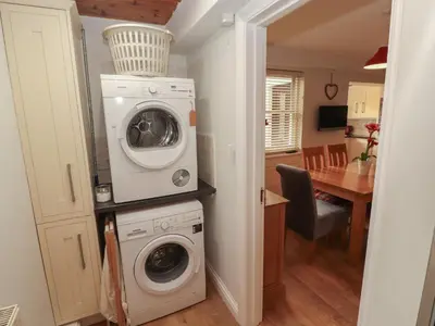 a laundry room with a washer and dryer next to a kitchen at Riverside Cottage in Cockermouth