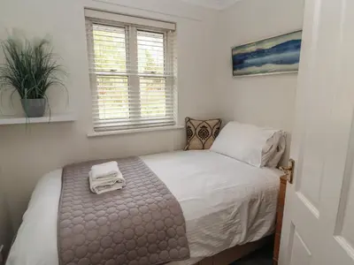 a bedroom with a bed with white sheets and a window at Riverside Cottage in Cockermouth