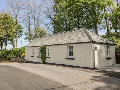 a small white building with a roof on a street at Garden Cottage in Castle Douglas
