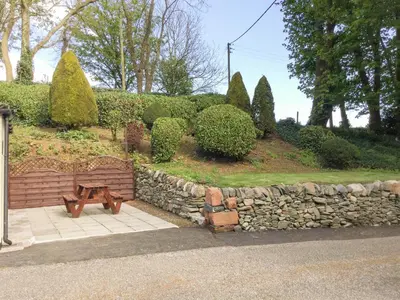 a wooden bench sitting next to a stone wall at Garden Cottage in Castle Douglas
