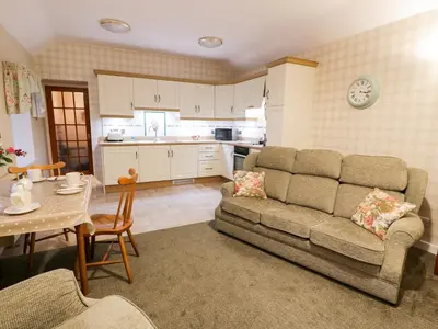 a living room with a couch and a table at Garden Cottage in Castle Douglas