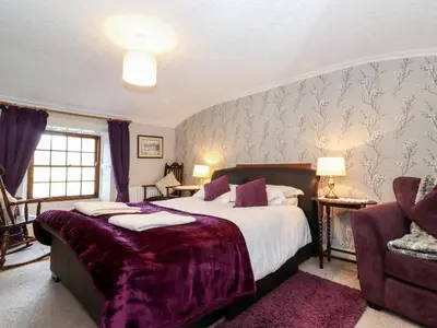a bedroom with a large bed with a purple blanket at Castle Lodge in Keswick