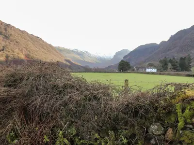 a field with a fence and mountains in the background at Castle Lodge in Keswick