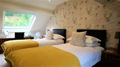 two beds in a hotel room with a wall with antlers at Fern Howe Guest House in Keswick
