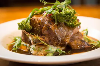a plate of food with meat and broccoli on a table at The Horse and Farrier Inn and The Salutation Inn Threlkeld Keswick in Threlkeld