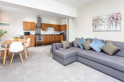 a living room with a couch and a table and a kitchen at Granary Suite No3 - Donnini Apartments in Ayr