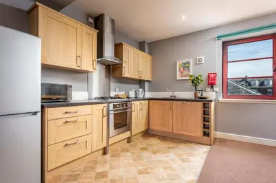 a kitchen with wooden cabinets and a window at Elliot Suite No15 - Donnini Apartments in Ayr