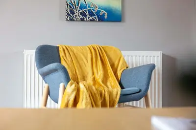 a blue chair with a yellow blanket on it at Elliot Suite No15 - Donnini Apartments in Ayr
