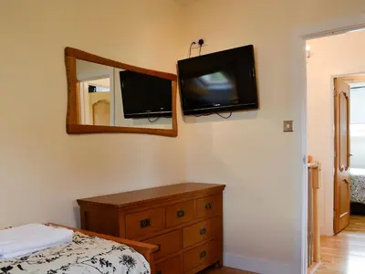 a bedroom with a dresser and a tv on the wall at Ghillie Cottage in Cockermouth