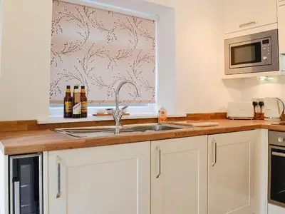 a kitchen with a sink and a microwave at Ghillie Cottage in Cockermouth