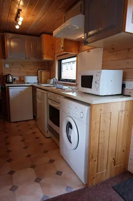 a kitchen with a washing machine and a microwave at Fellside Lodge in Keswick