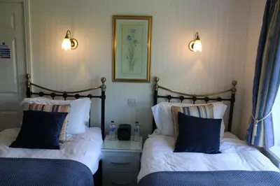 two beds in a room with two lamps on the wall at Link House in Bassenthwaite Lake