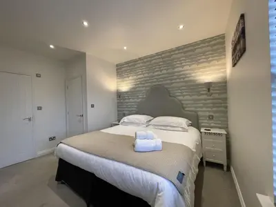 a bedroom with a large bed and a brick wall at Isabel Cottage in Keswick