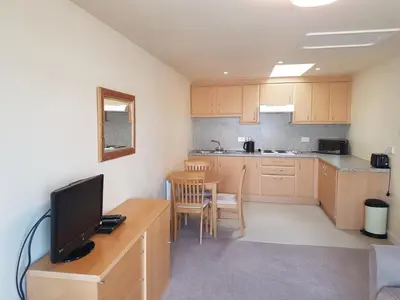 a kitchen with a desk with a television and a table at Fairways Cottages in Prestwick