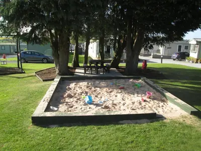 a sandbox in a park with toys in the sand at 27 The Beeches, Gilcrux, Nr Cockermouth, Cumbria in Gilcrux