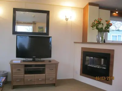 a living room with a television and a fireplace at 27 The Beeches, Gilcrux, Nr Cockermouth, Cumbria in Gilcrux