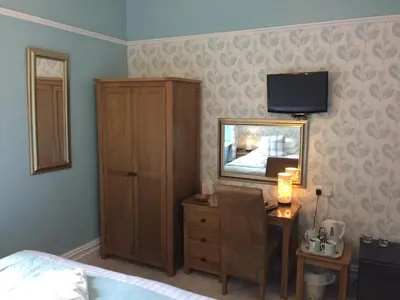 a bedroom with a bed and a dresser with a mirror at Ravensworth House in Keswick