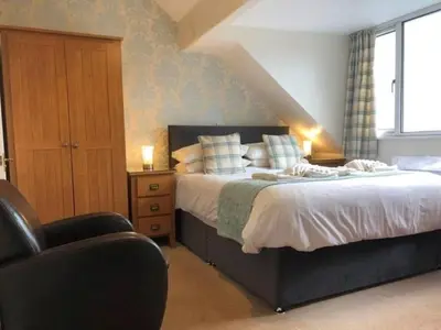 a bedroom with a large bed and a chair at Ravensworth House in Keswick
