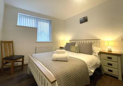 a bedroom with a bed and a chair and a window at Sam's Cottage in Keswick