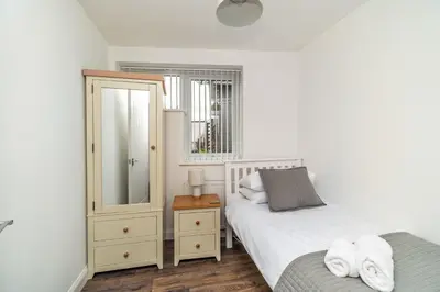 a bedroom with two beds and a dresser and a mirror at Sam's Cottage in Keswick