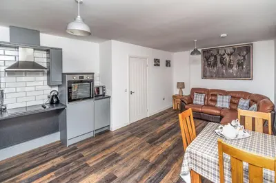 a kitchen and living room with a table and a couch at Sam's Cottage in Keswick