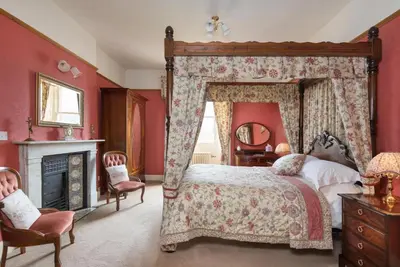 a bedroom with a large canopy bed and a fireplace at Acorn House in Keswick
