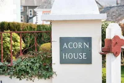 a sign on a house on a white fence at Acorn House in Keswick
