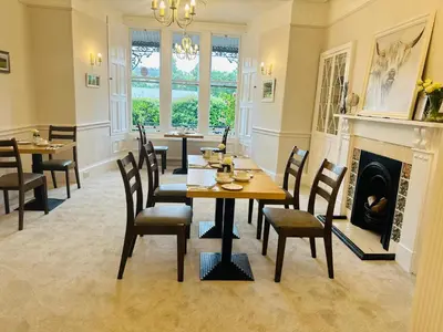 a dining room with a table and chairs and a fireplace at Buchan Guest House in Moffat