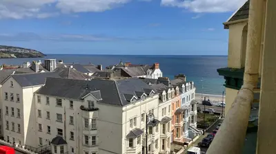 a view of a building with the ocean in the background at Welbeck Hotel & Apartments IOM in Douglas