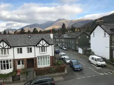 a town with cars parked on a street with mountains at Winchester House in Keswick