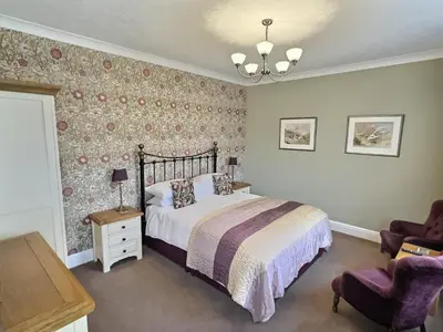 a bedroom with a bed and a chair at Three Shires Inn in Little Langdale