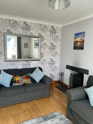 a living room with a couch and a mirror at Stanger Cottage in Keswick