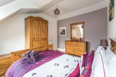 a bedroom with a large bed and a wooden dresser at Stanger Cottage in Keswick