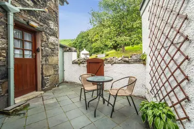 a patio with a table and chairs and a door at Stanger Cottage in Keswick