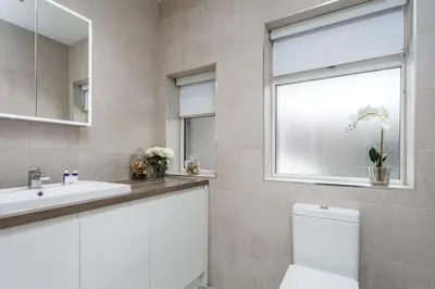 a bathroom with a sink and a toilet and a window at The Alexander - Donnini Deluxe in Prestwick