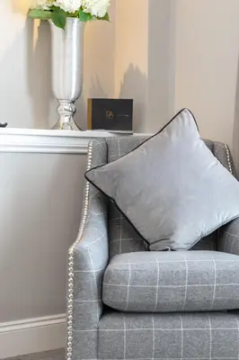 a gray couch with a vase and a pillow on it at The Alexander - Donnini Deluxe in Prestwick