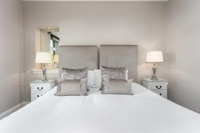 a bedroom with a large white bed with two lamps at The Alexander - Donnini Deluxe in Prestwick