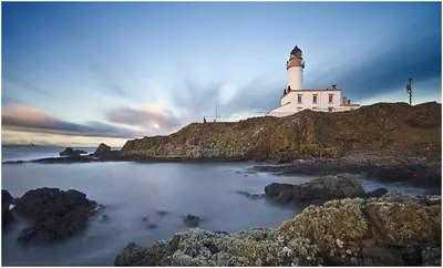 a lighthouse sitting on top of a rocky island at Turnberry Serviced Apartments in Turnberry