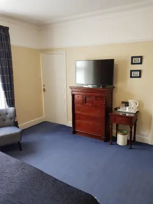 a living room with a tv on a dresser with a desk at Hamilton House in Dumfries