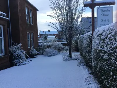 a snow covered sidewalk next to a building with a sign at Hamilton House in Dumfries